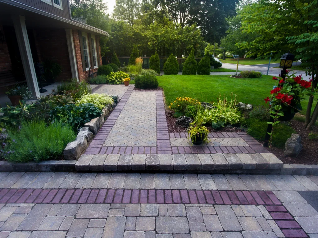 Ground-level view toward the house showing the bordered interlock walkway and driveway edge in Ancaster.