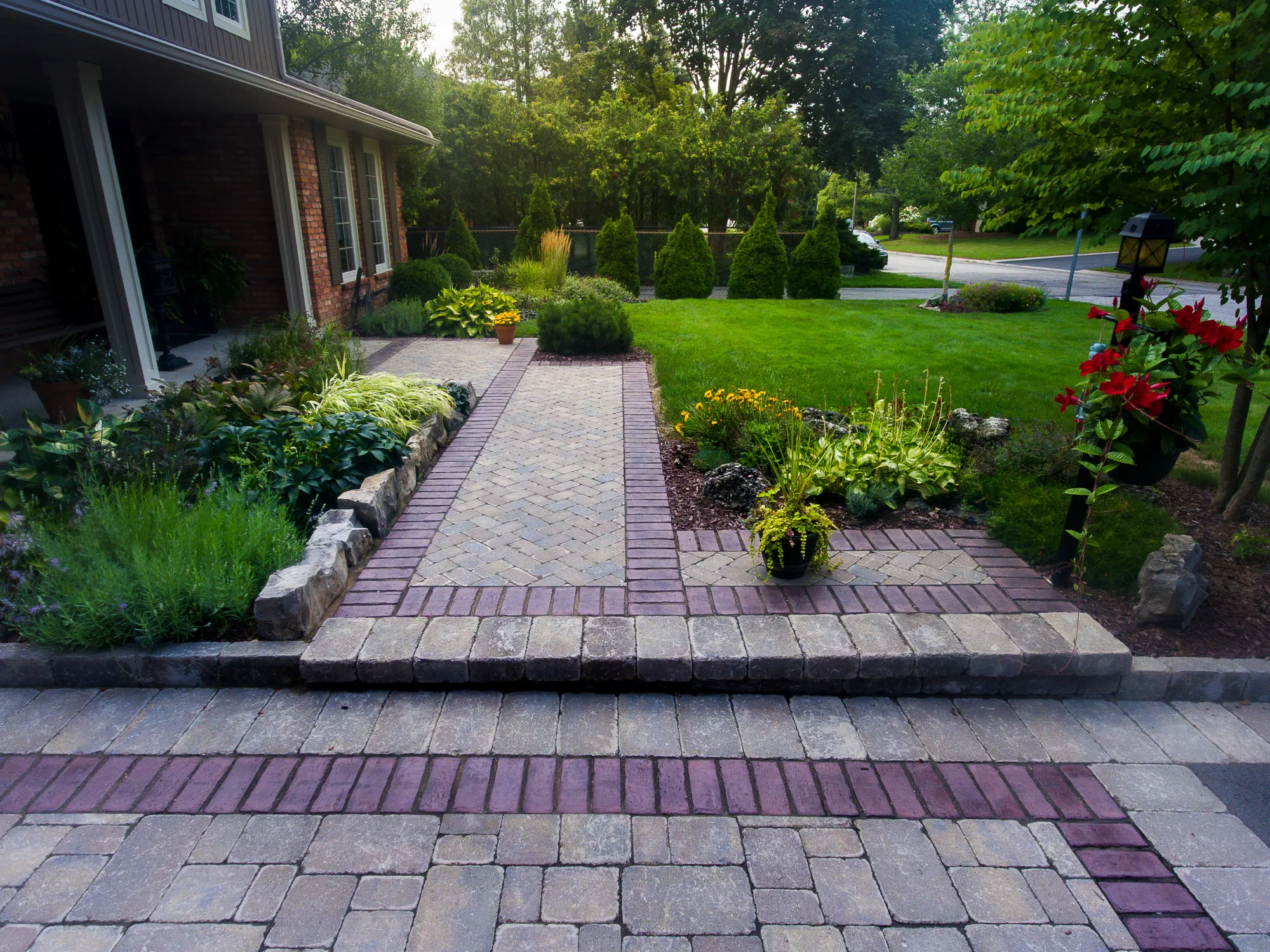 Ground-level view toward the house showing the bordered interlock walkway and driveway edge in Ancaster.