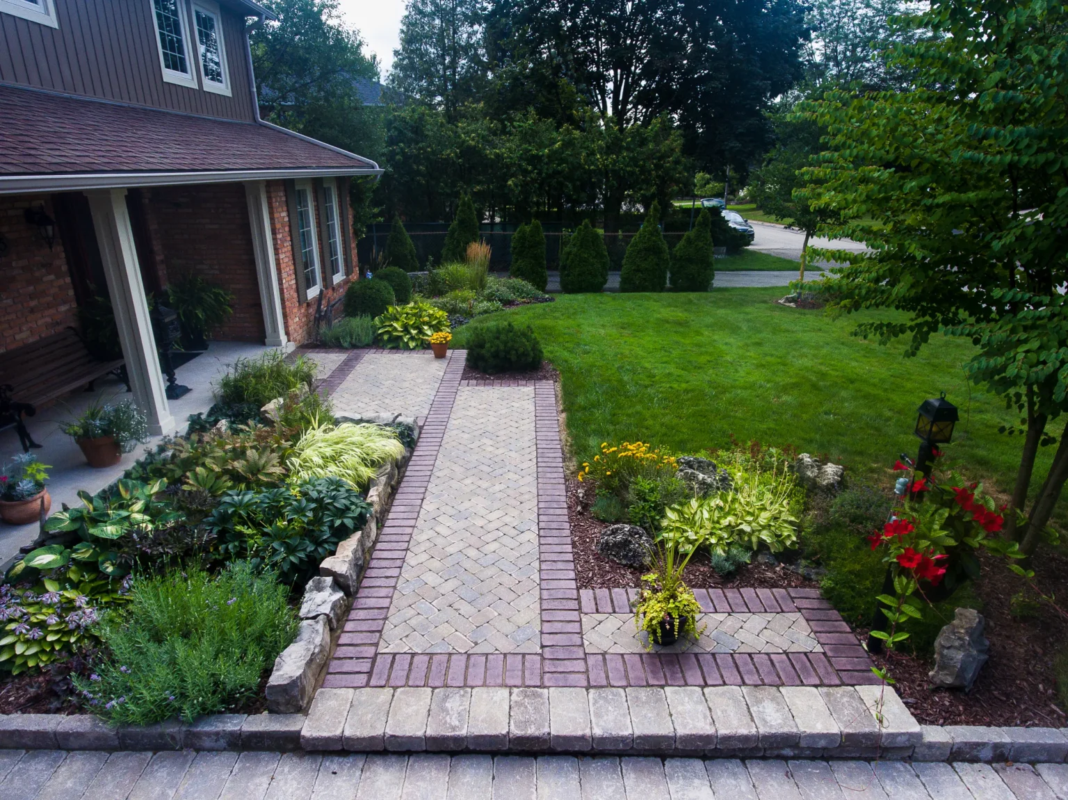 Ground-level view of a light interlock front walkway with contrasting border and planted beds in Ancaster.