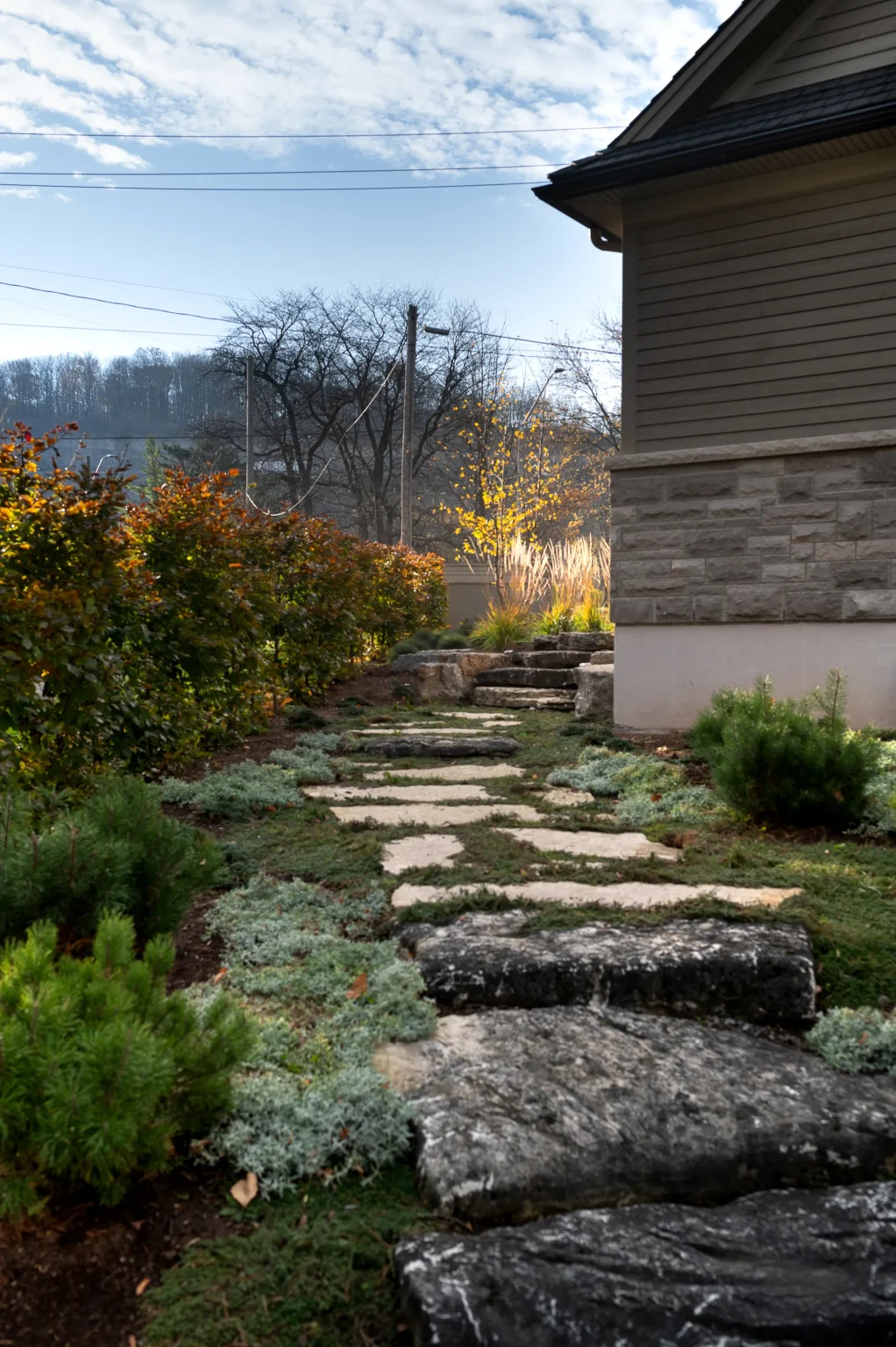 Portrait view of a natural stone path and steps framed by fall foliage in Ancaster.