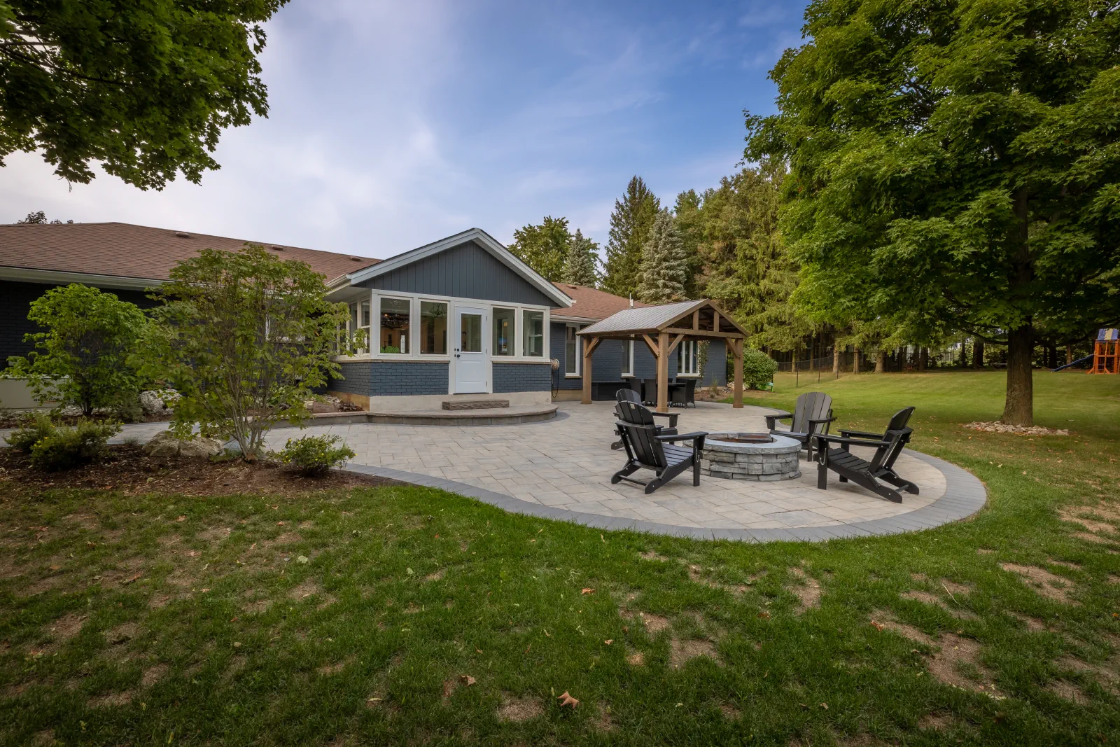 Brantford backyard with an interlock patio, circular fire pit and timber pergola.