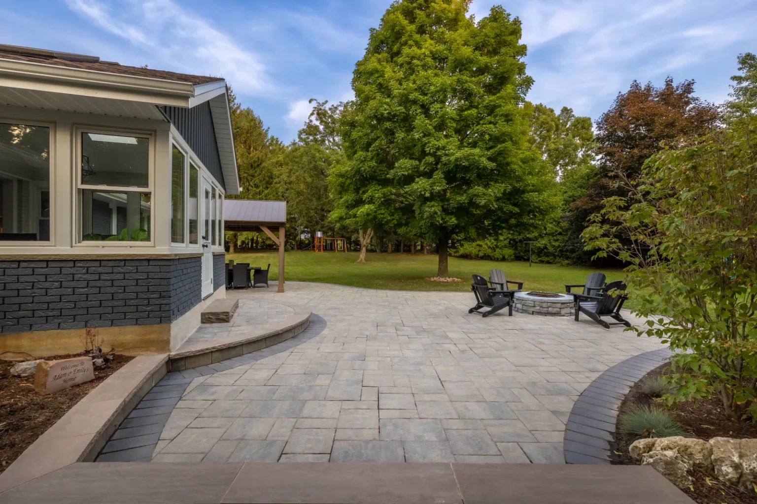 Wide view of a curved interlock backyard patio and steps in Brantford.