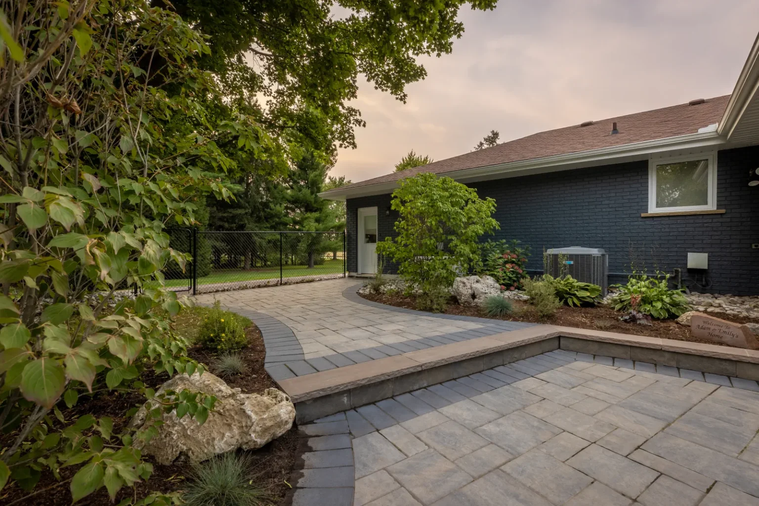 Curved interlock patio steps beside a planted garden bed in Brantford.