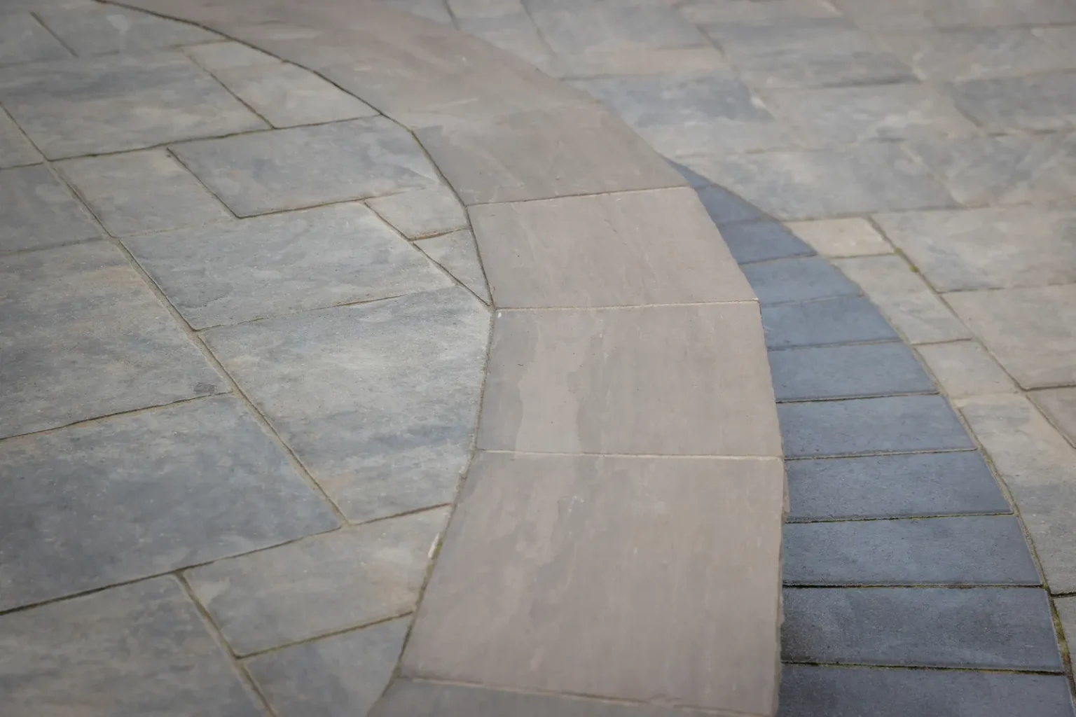 Close detail of a curved interlock paver border on a Brantford patio.