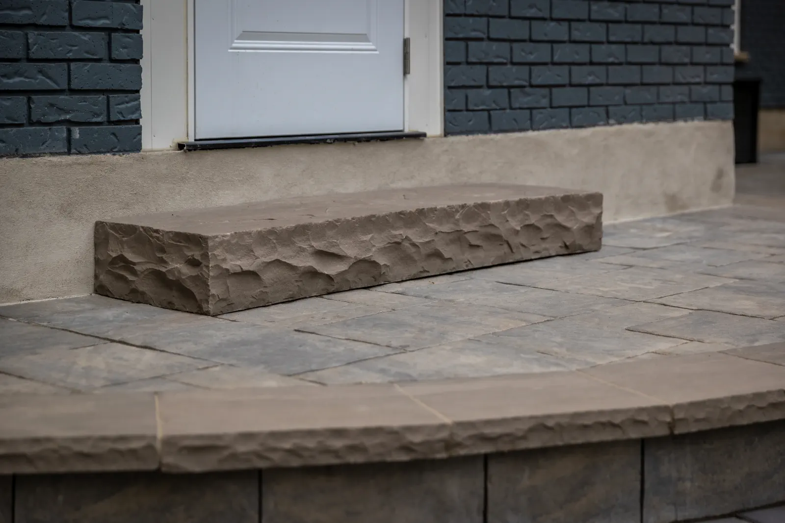 Close detail of a textured stone step on an interlock patio in Brantford.