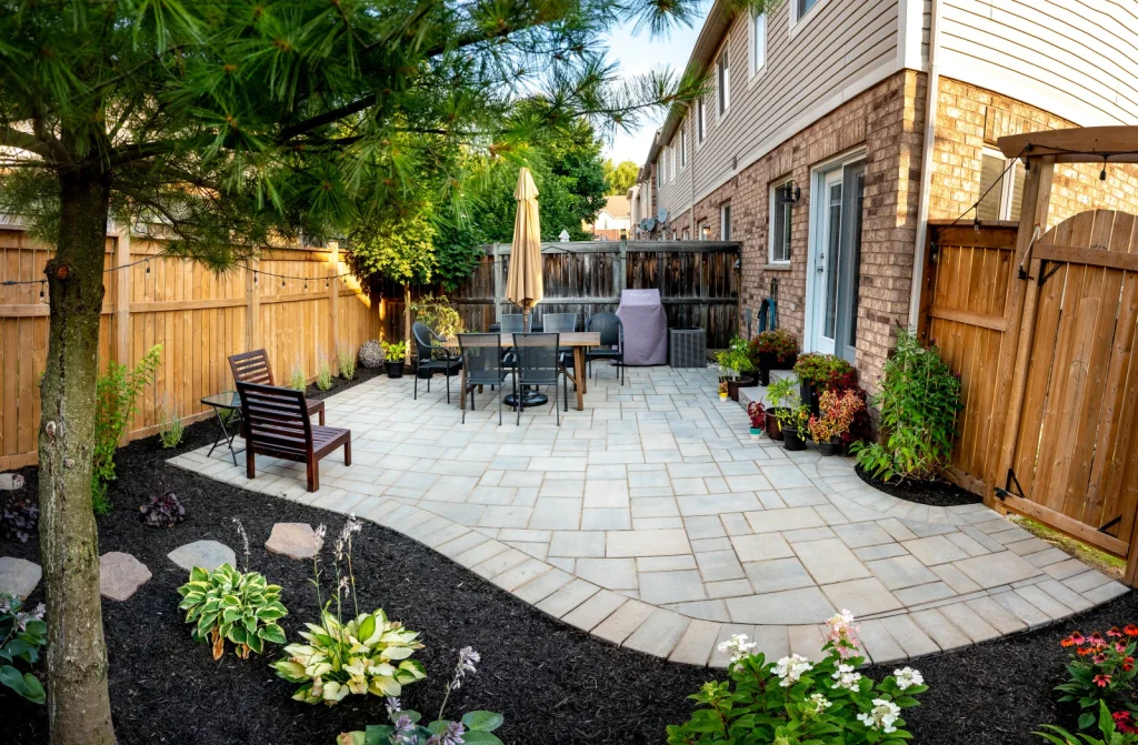 Completed small Burlington backyard with an interlock patio, dining area and planting beds.