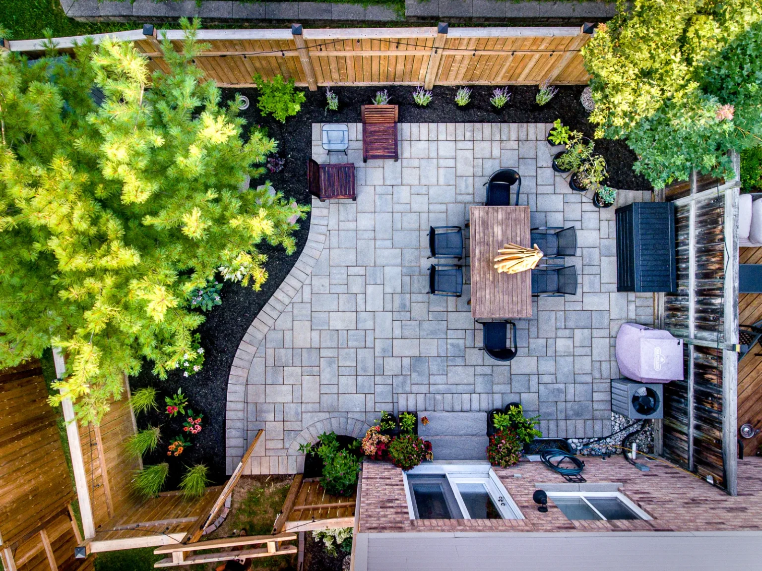 Aerial view of a small Burlington backyard with an interlock patio, dining area and planted borders.
