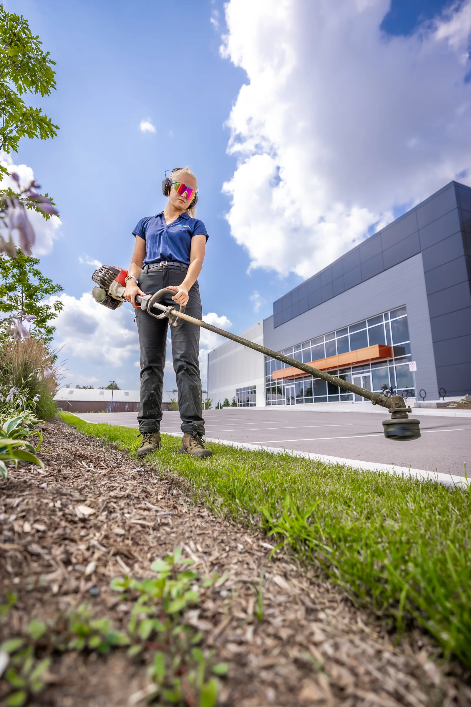 Creative Concepts crew member string trimming beside a commercial landscape bed.