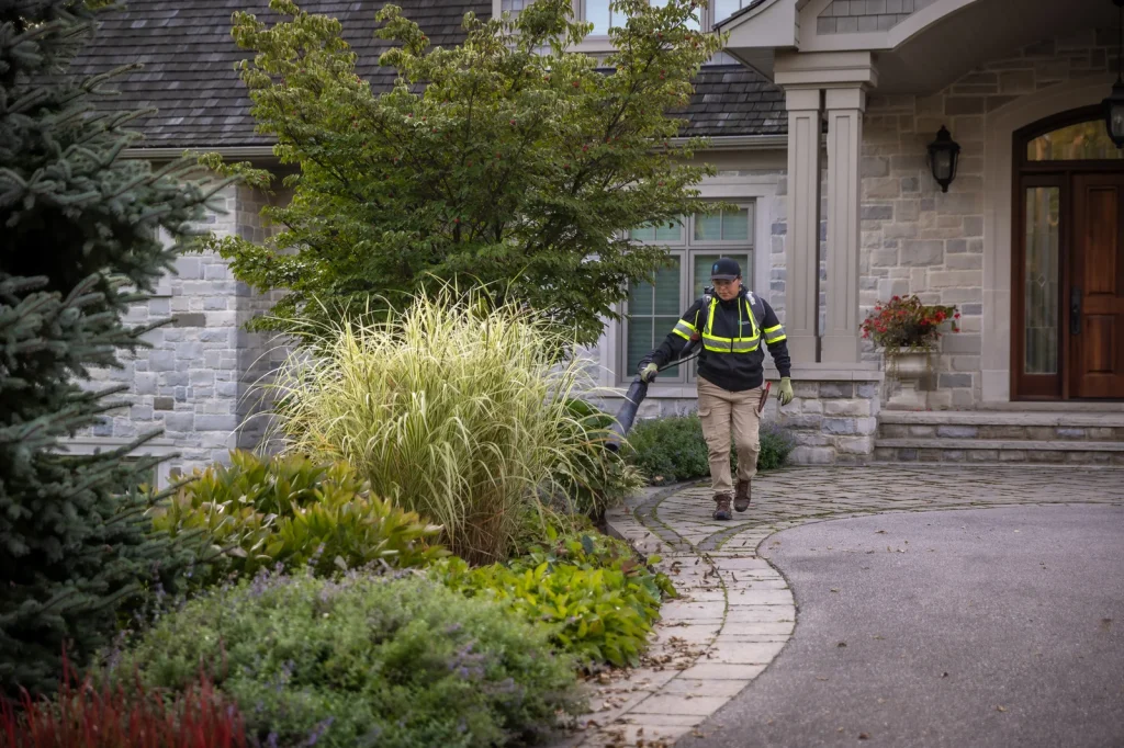 Creative Concepts crew member carrying equipment through a landscaped front entry.