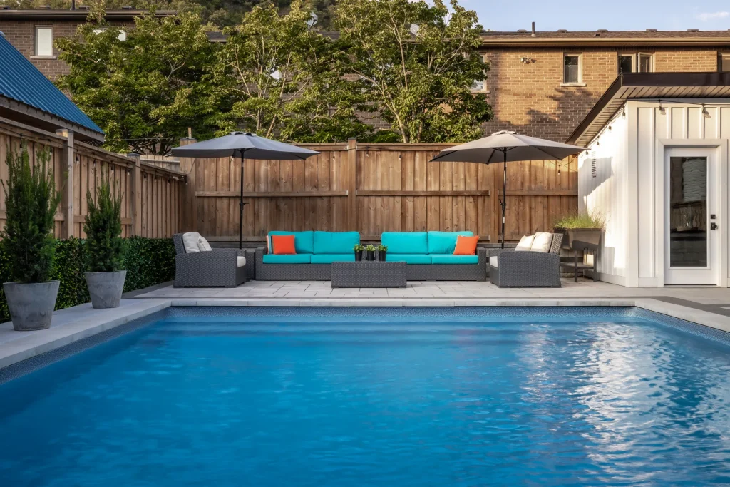 Straight-on view across the rectangular pool toward colourful lounge seating in Dundas.