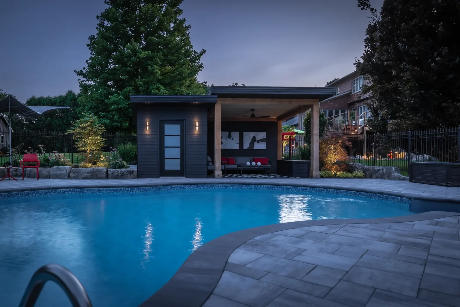 Blue-hour view across the pool toward the illuminated cabana in Dundas.
