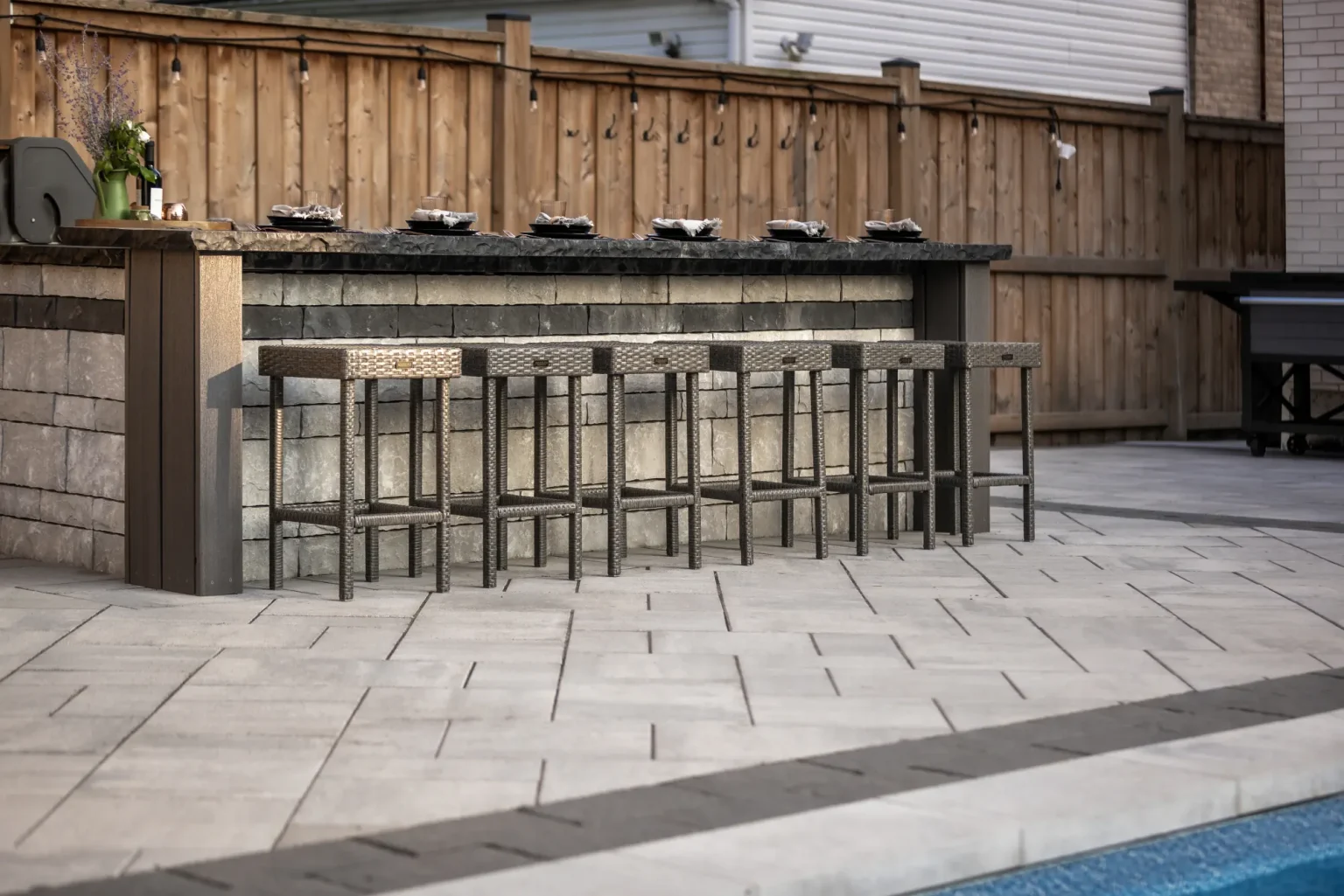 Built-in outdoor bar with stools on the modern paver patio in Dundas.