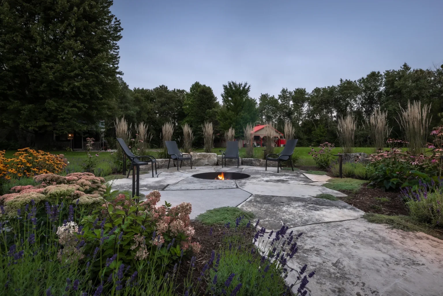 Daylight view of the natural-stone fire-pit garden surrounded by perennials in Dundas.