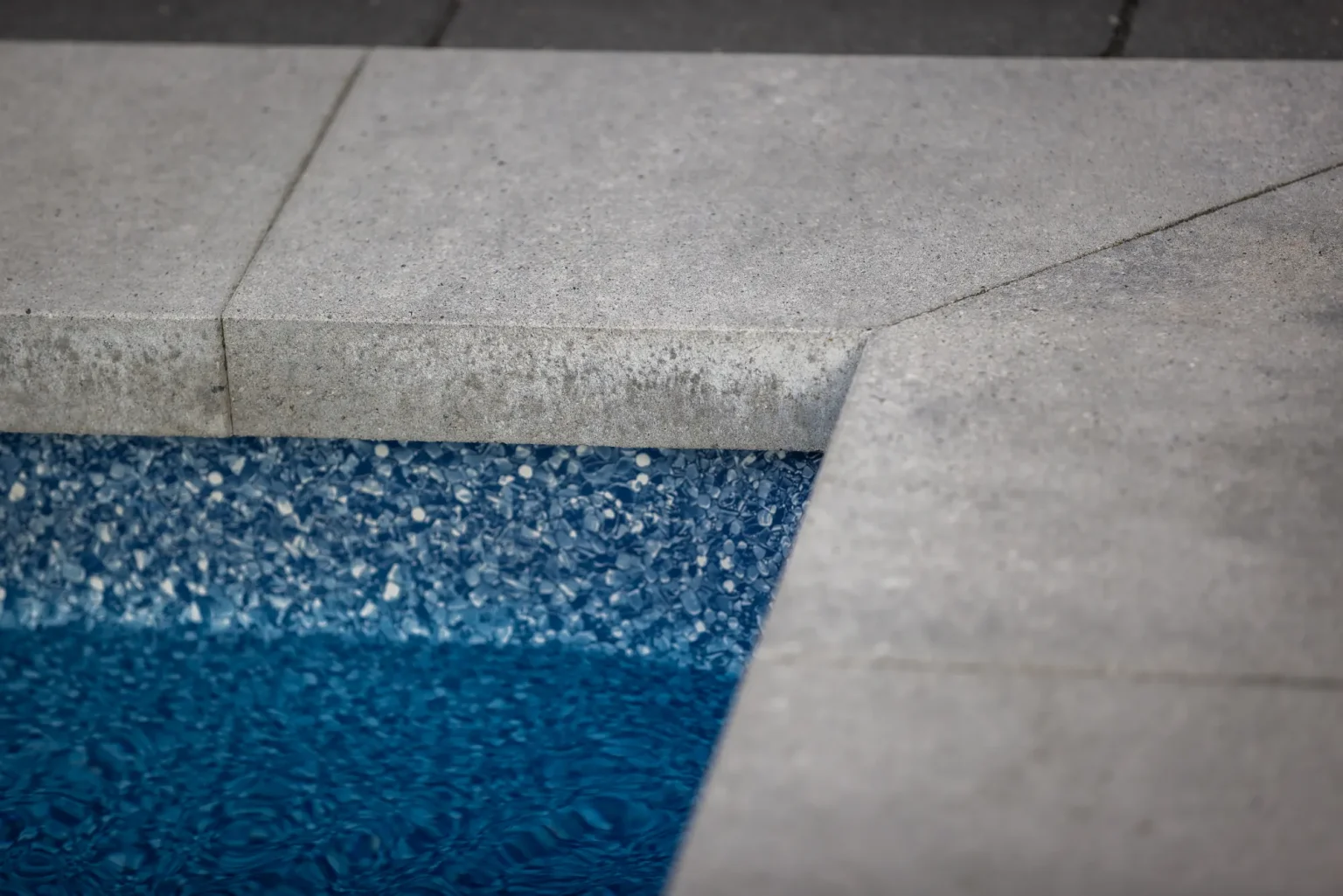 Close detail of the pool coping and blue waterline finish in Dundas.