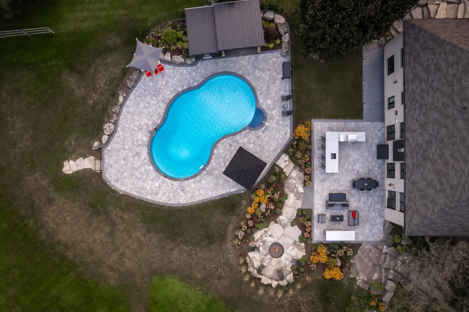 Top-down drone view of the curved pool, patio and fire-pit garden in Dundas.