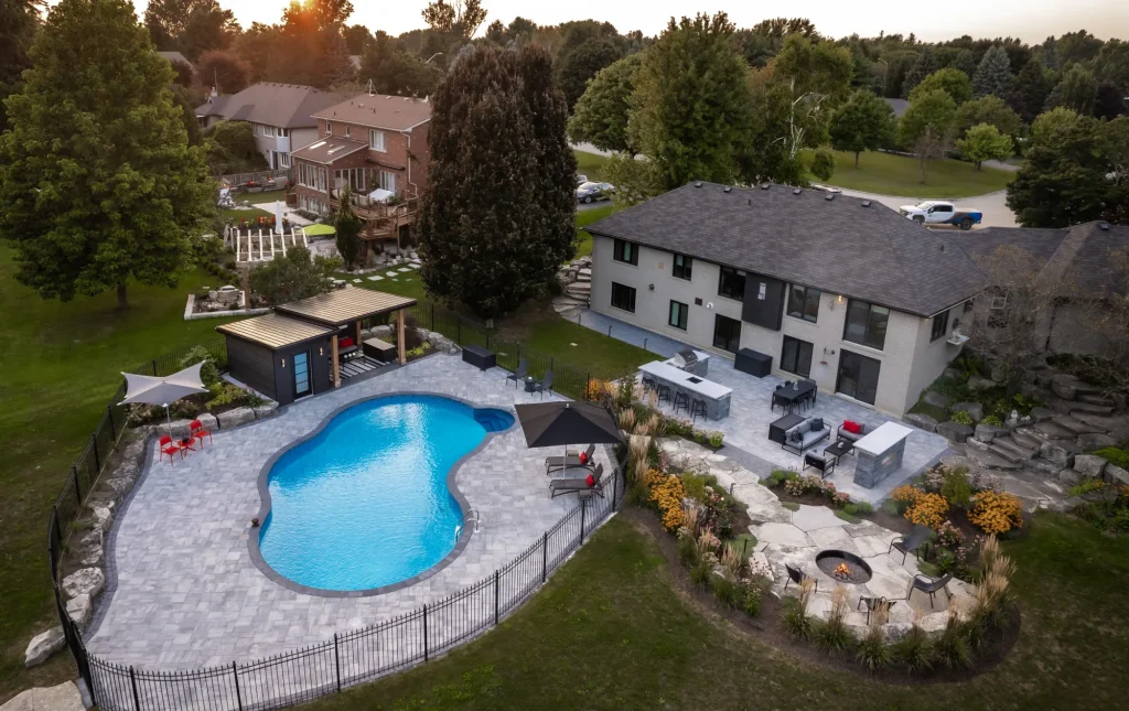 Wide drone overview of the residential backyard and curving pool landscape in Dundas.