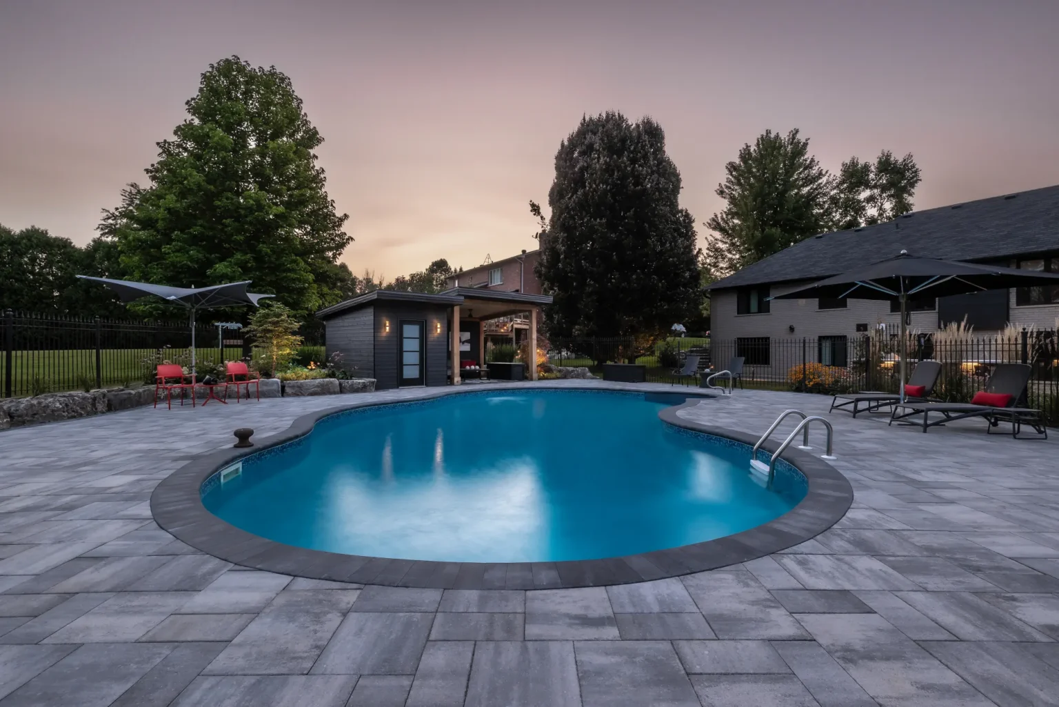 Wide dusk pool view with the cabana and landscape beyond in Dundas.