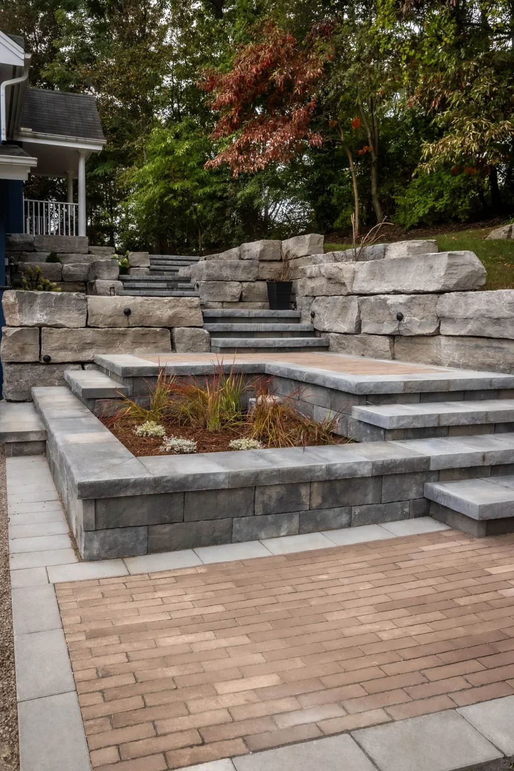 Vertical view along stepped stone levels and low garden retaining walls rising toward the blue house in Dundas.