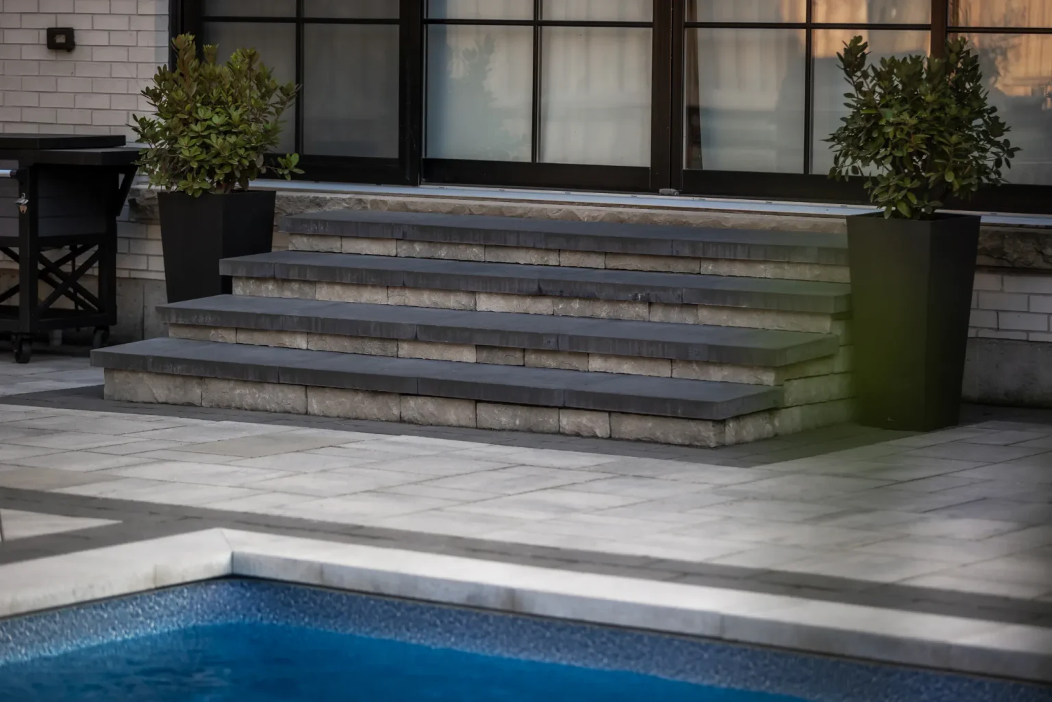 Broad masonry steps meeting the pool patio and coping in Dundas.