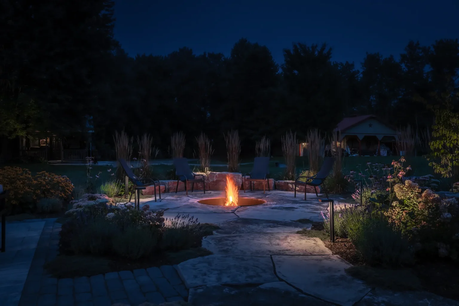 Natural-stone fire-pit garden glowing at night in Dundas.