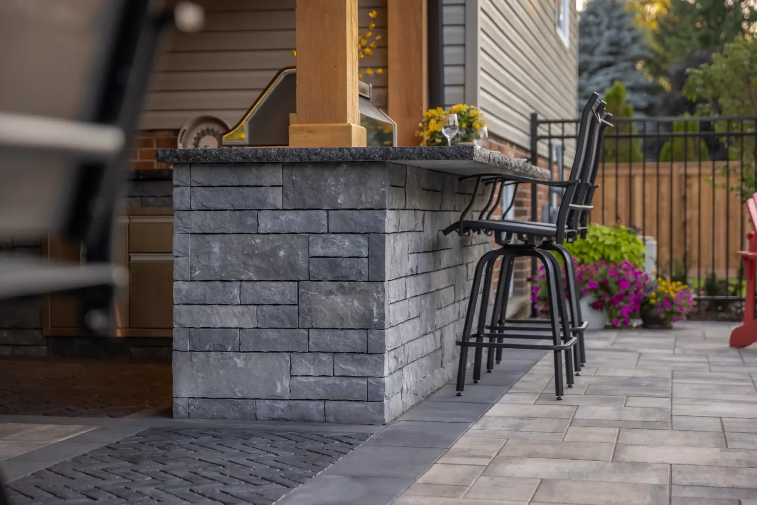 Stone-clad bar and seating beside the house under the Dundas timber frame.