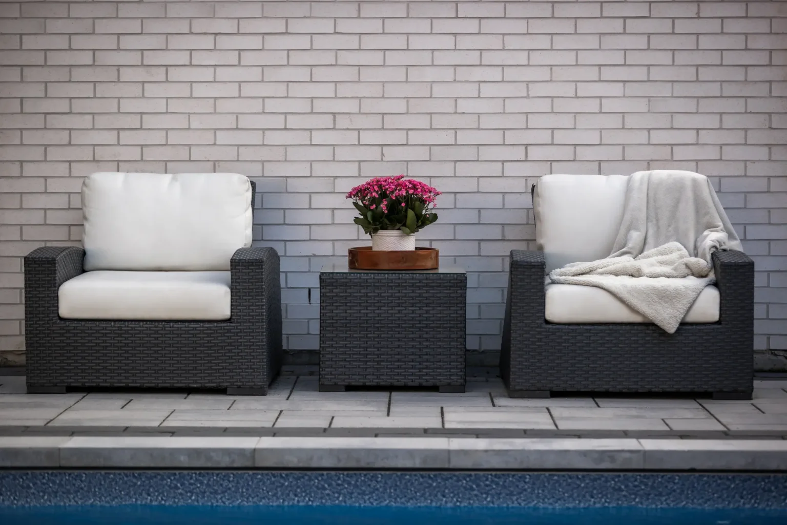 Pair of lounge chairs beside the rectangular pool and brick home in Dundas.