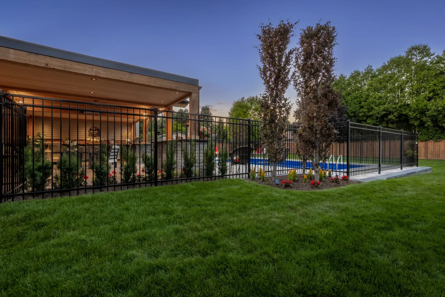 Black metal pool fence and landscaped lawn beside a Dundas backyard pool area.