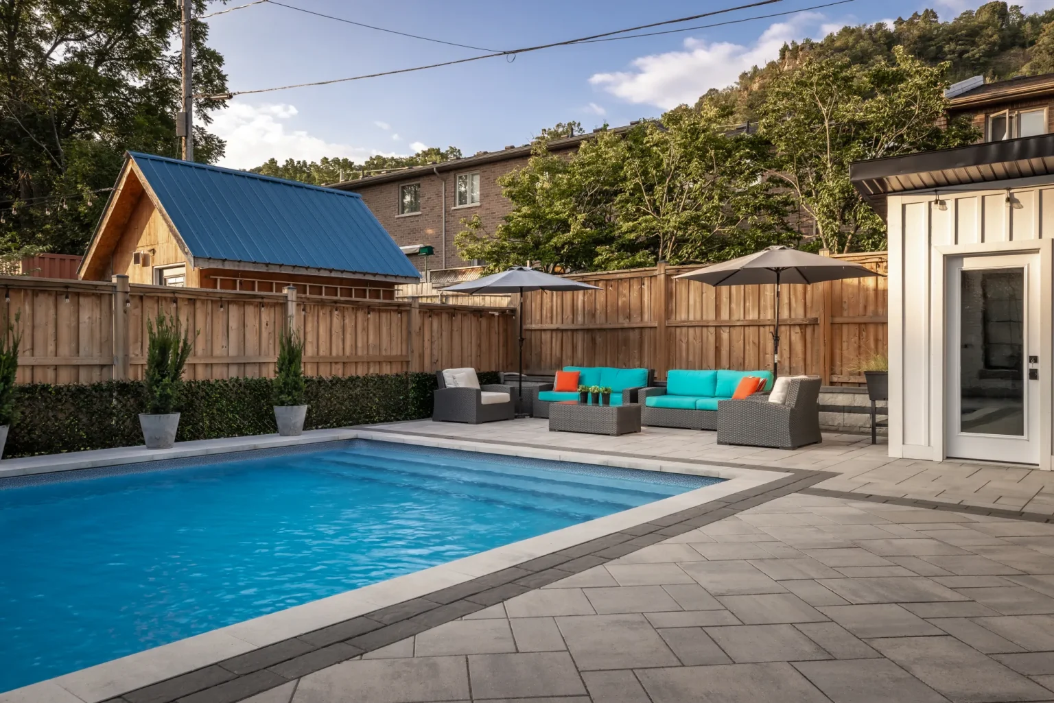 Wide pool view toward lounge seating and a small accessory building in Dundas.