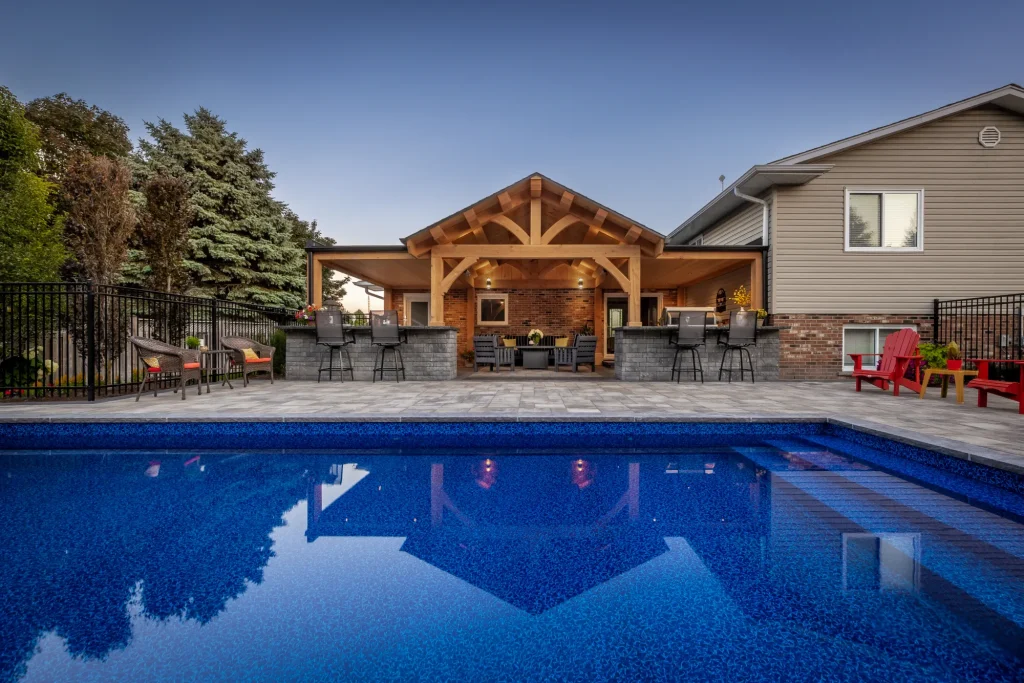 Evening view across the Dundas pool toward the timber-framed house extension and outdoor bar.