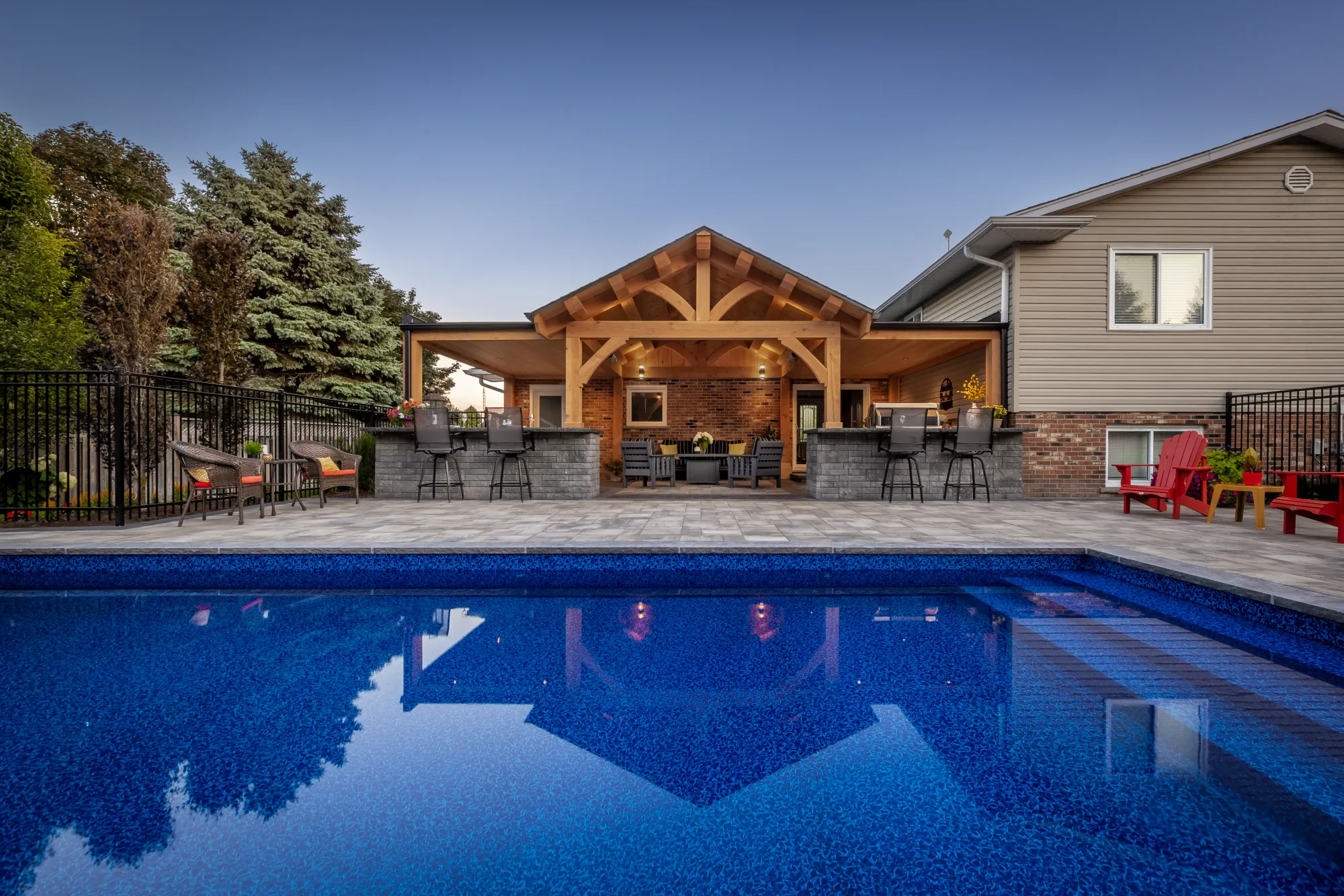 Evening view across the Dundas pool toward the timber-framed house extension and outdoor bar.