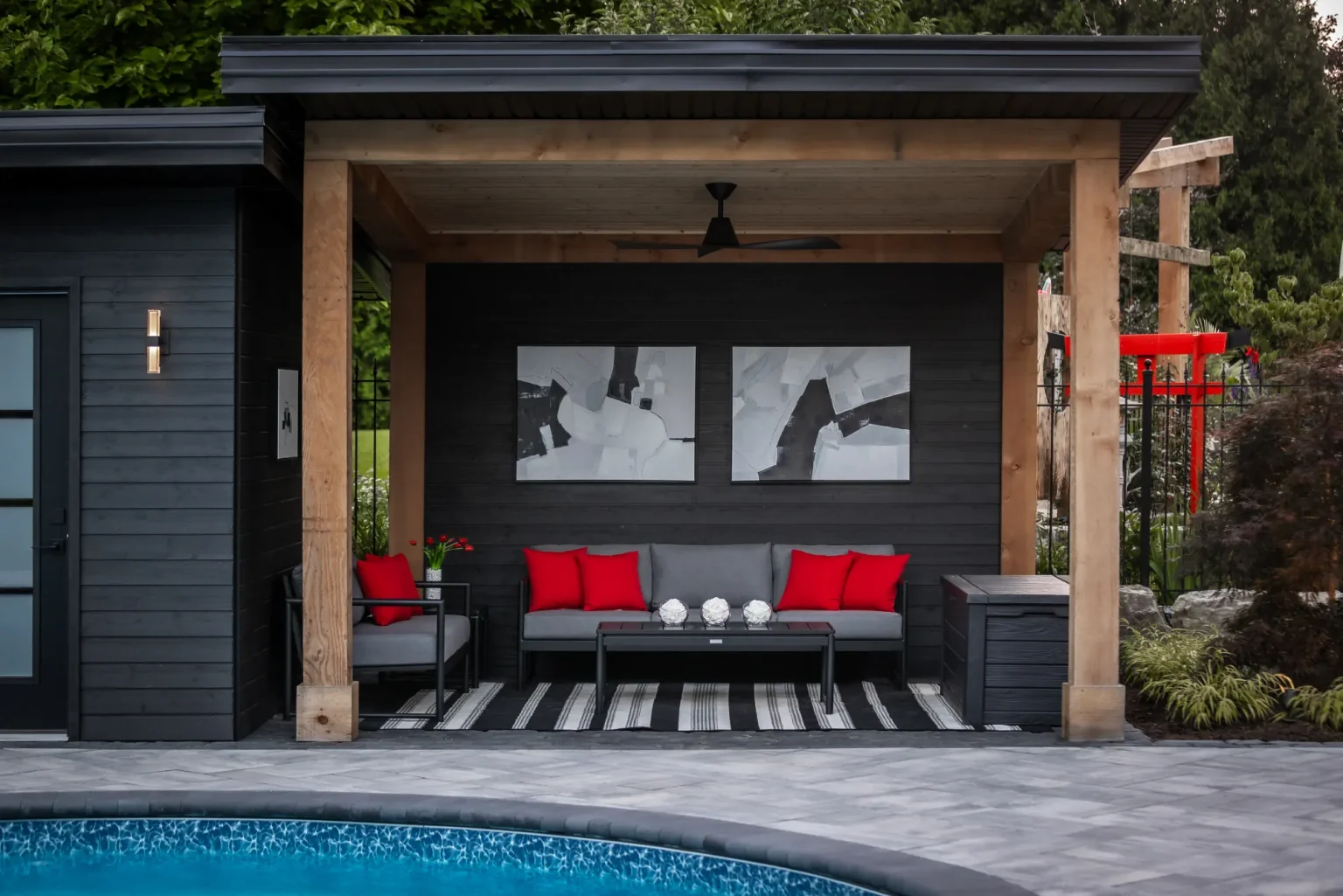 Poolside cabana with covered lounge seating and dark contemporary cladding in Dundas.