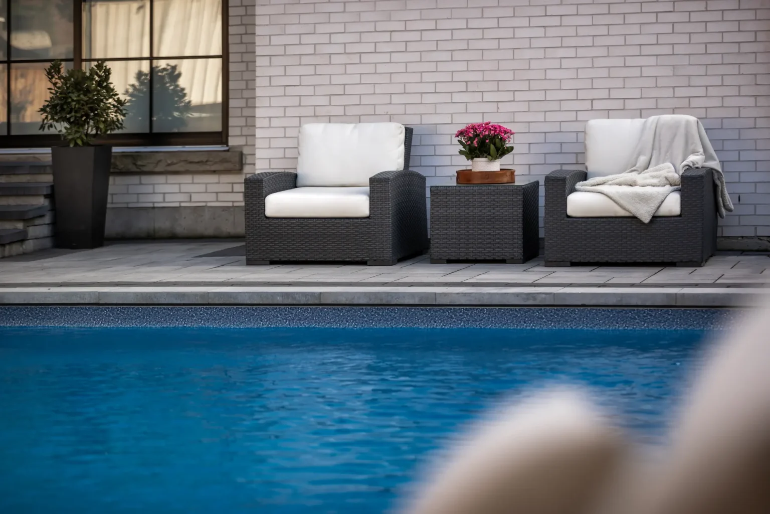 Poolside lounge seating against the brick home in Dundas.