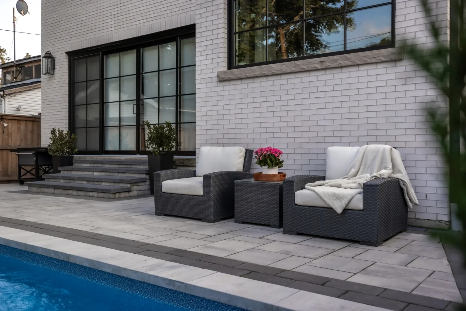 Poolside lounge seating against the brick house and modern steps in Dundas.