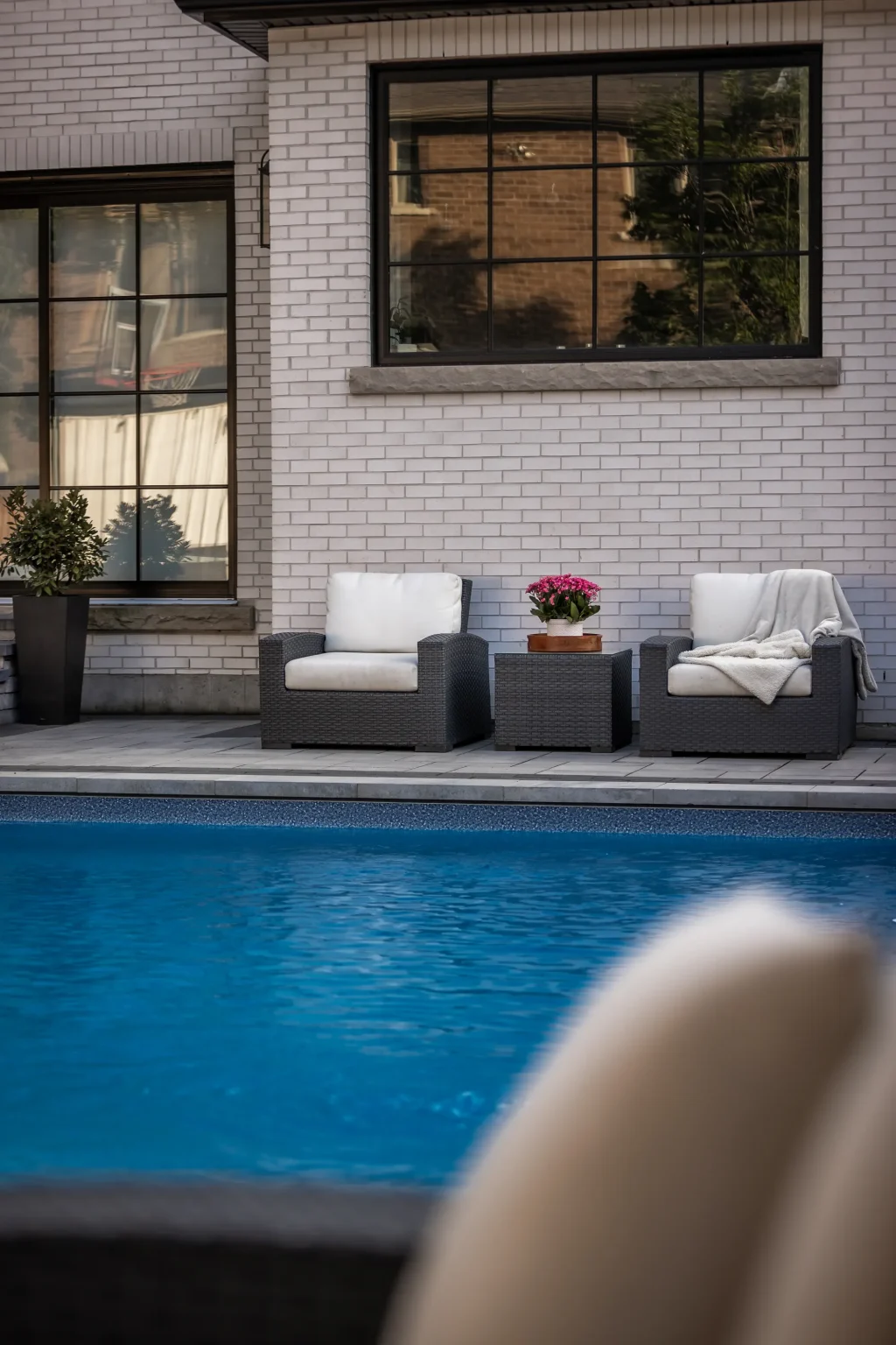 Portrait poolside seating view with the pool in the foreground in Dundas.
