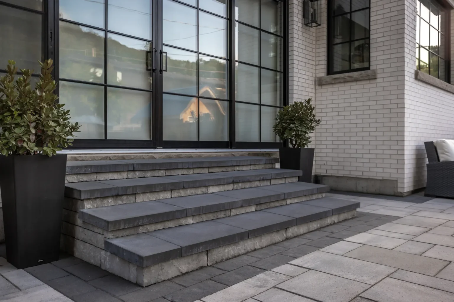 Broad rear steps against the modern brick home, surrounded by large-format pavers in Dundas.