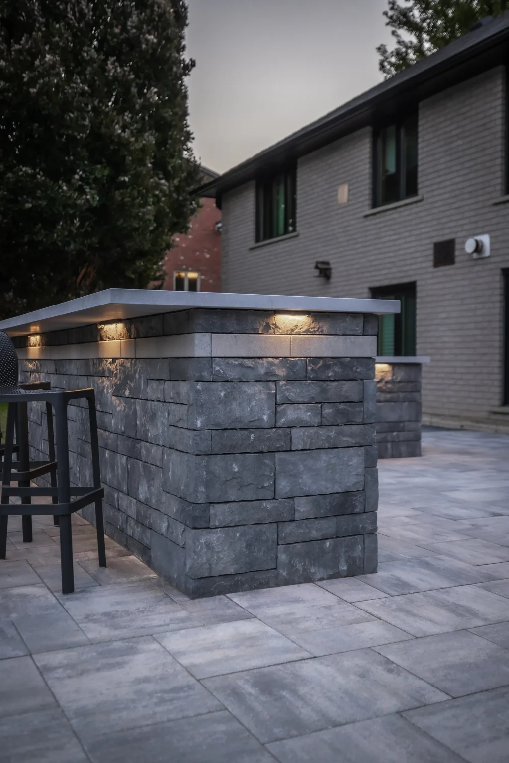 Portrait side view of the outdoor kitchen wall and paver patio beside the house in Dundas.