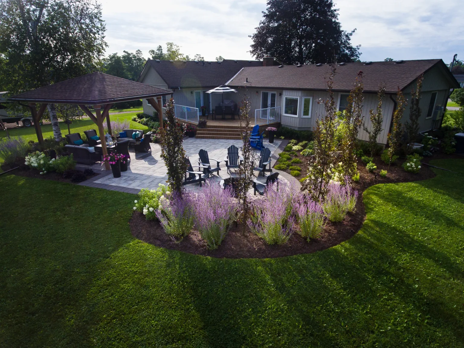 Ground-level wide view across the lawn toward the pavilion, patio and flowering garden in Flamborough.