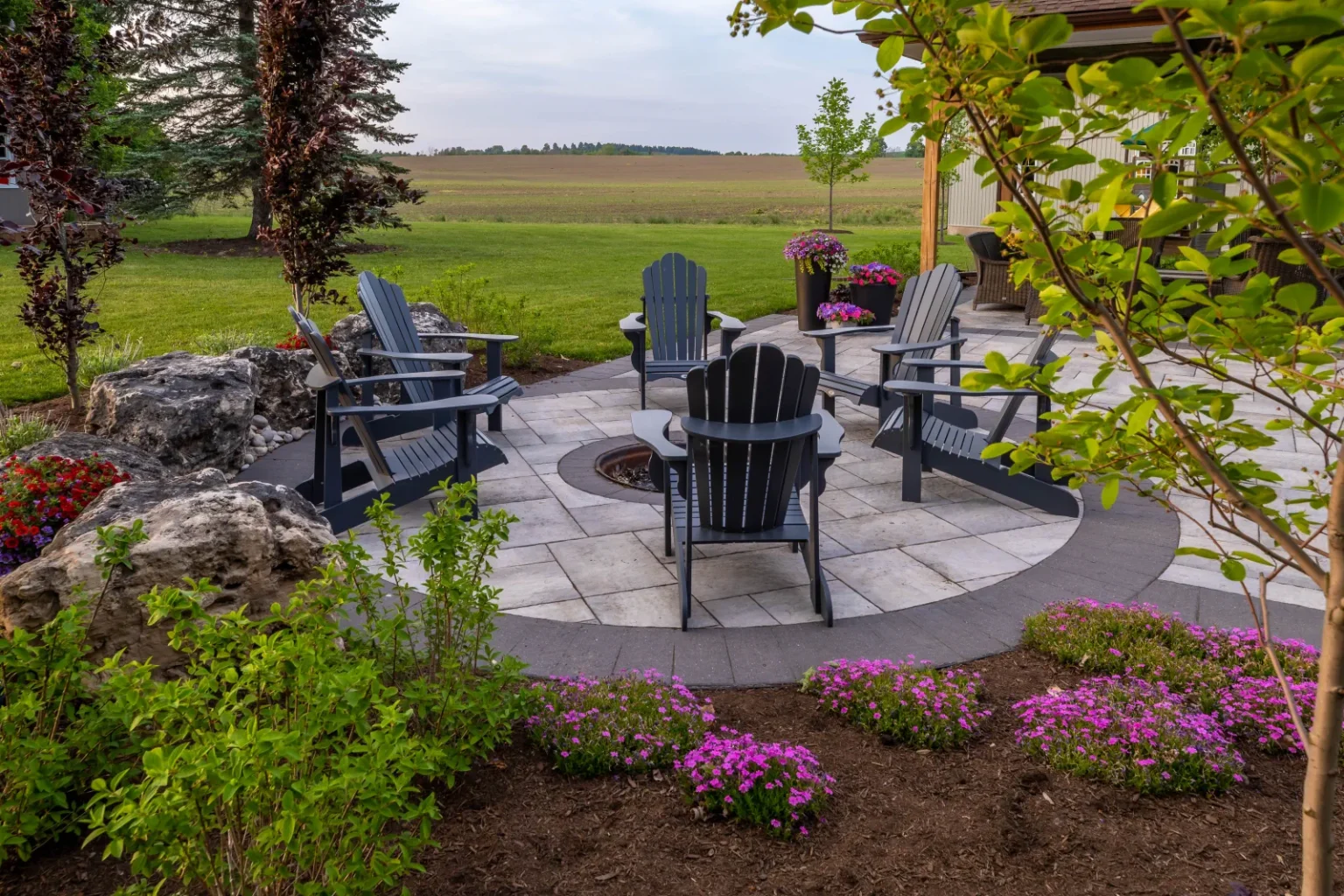 Closer view of the fire-pit circle with chairs, boulders and planted border in Flamborough.