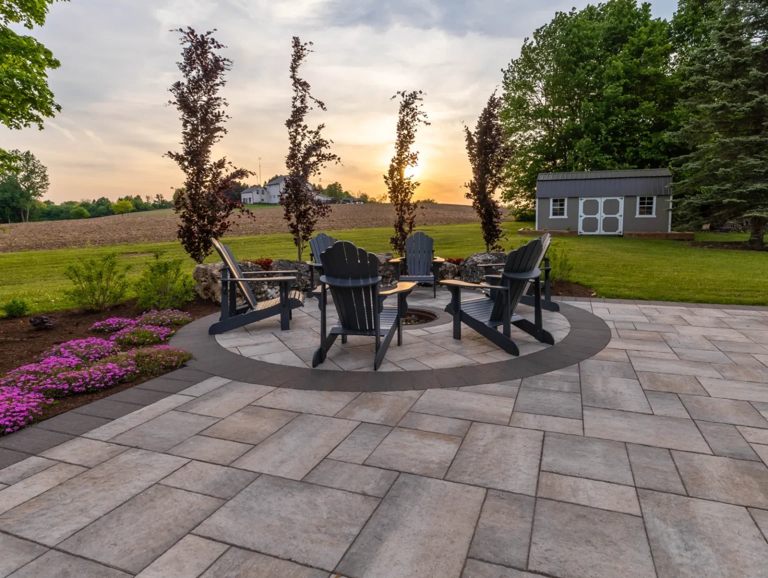 Fire-pit seating circle at sunset viewed from the paver patio in Flamborough.