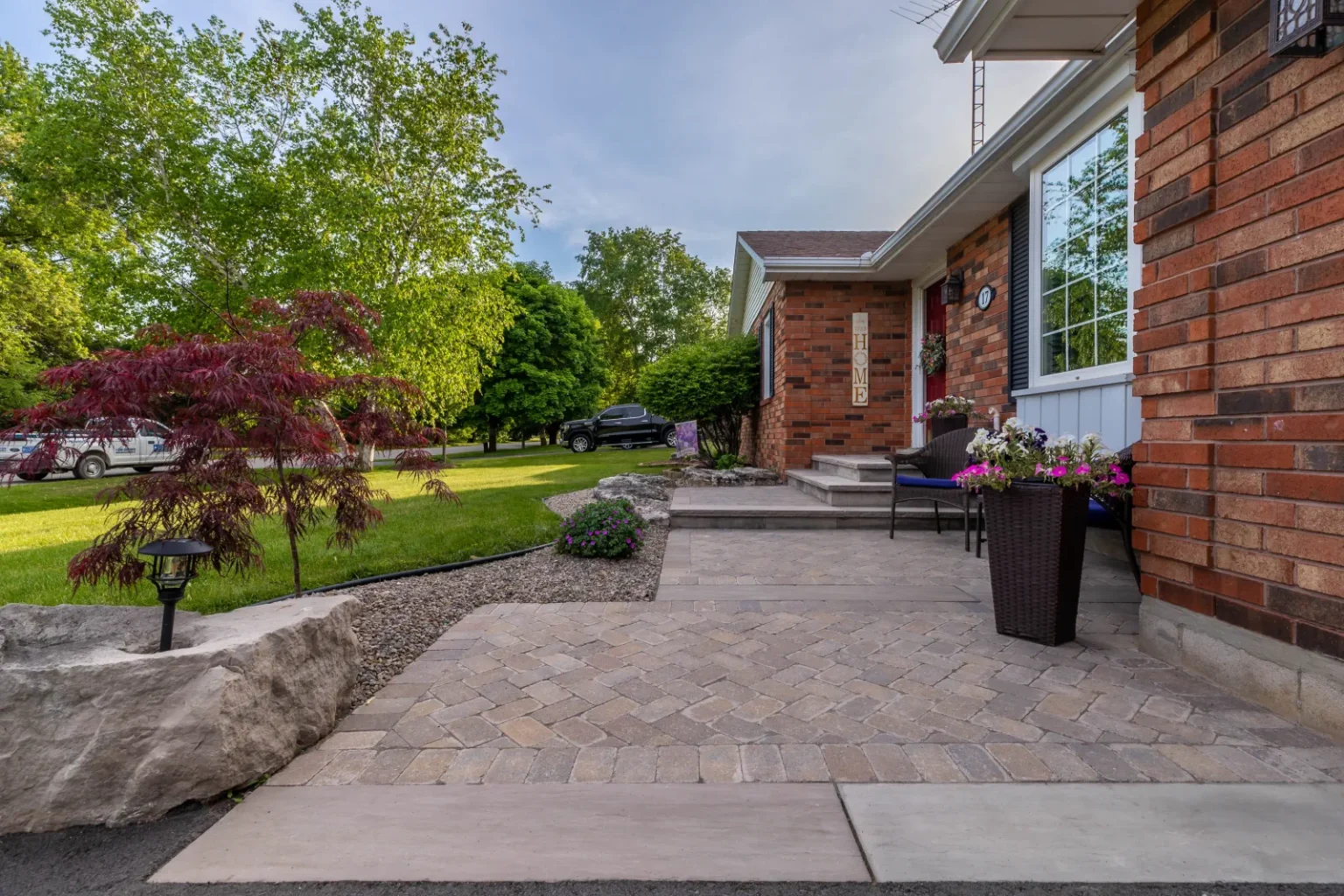 Front approach with interlock paving and a boulder-edged planted bed in Flamborough.