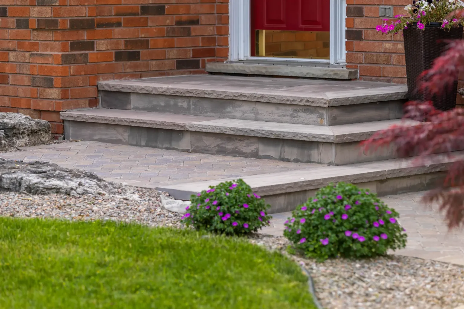 Natural stone front porch steps and landing framed by low flowering planting in Flamborough.