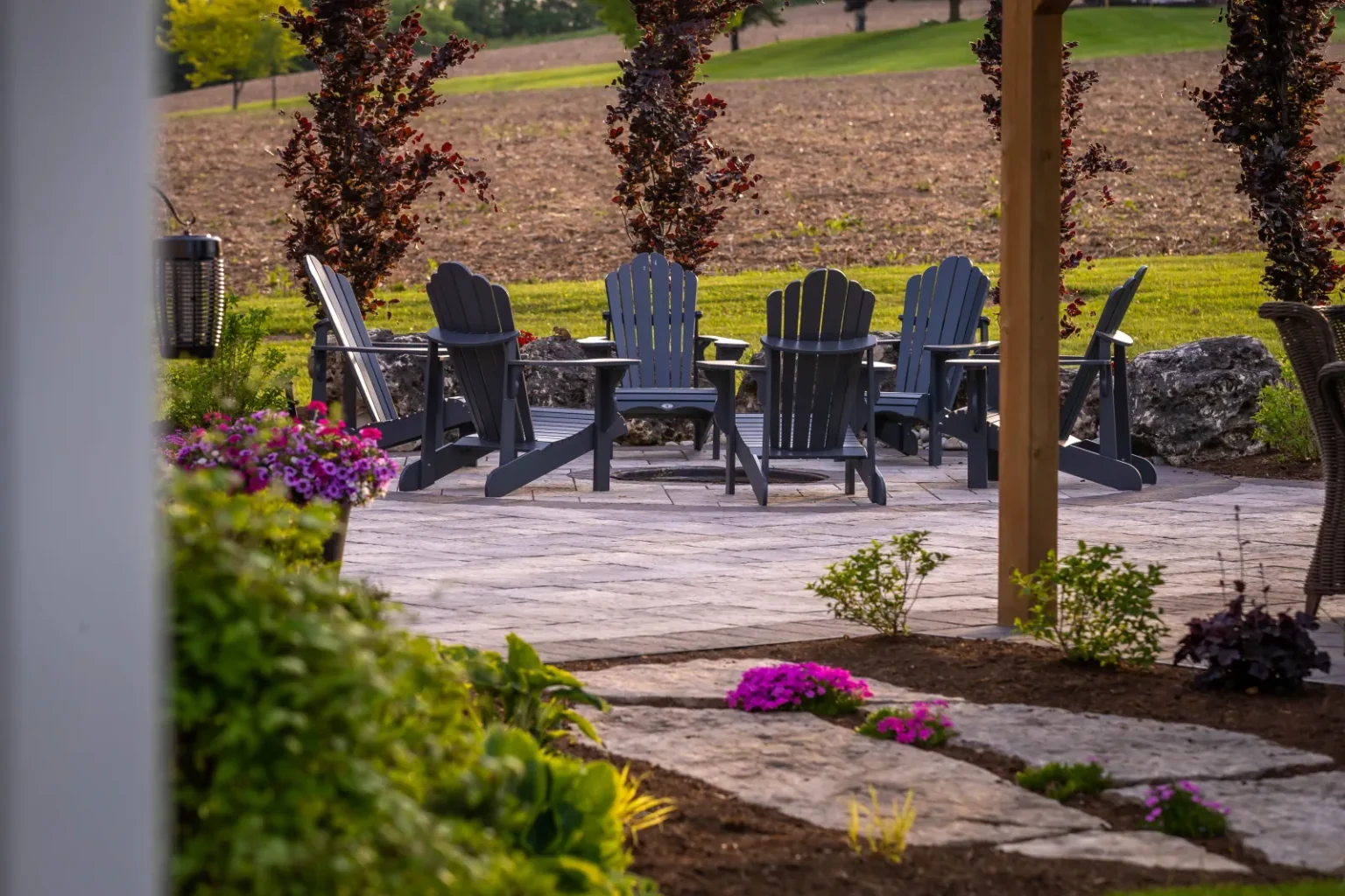 Outdoor fire-pit seating area viewed through layered garden planting in Flamborough.