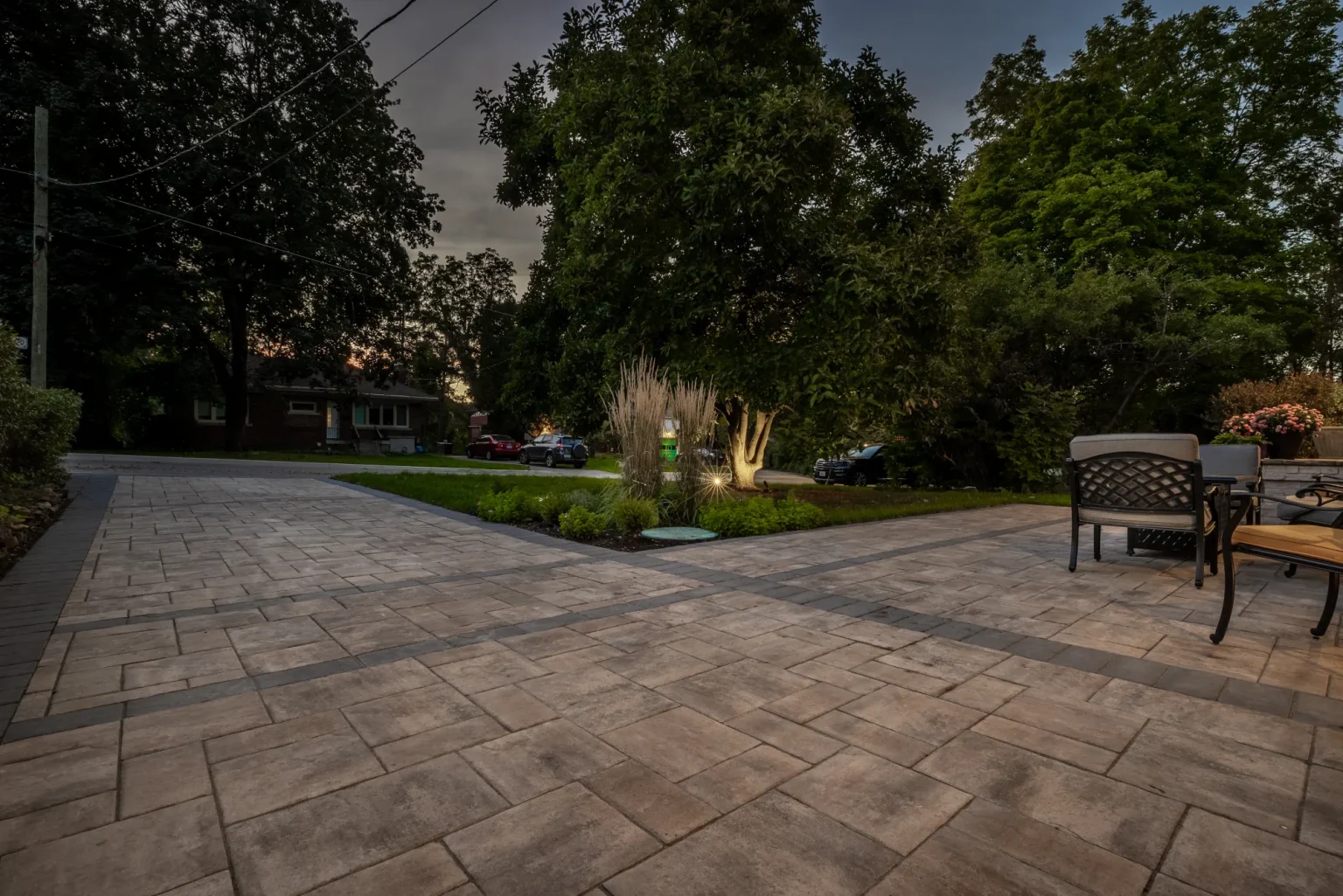 Wide paver patio and driveway transition with landscape lighting and a mature tree in Hamilton.