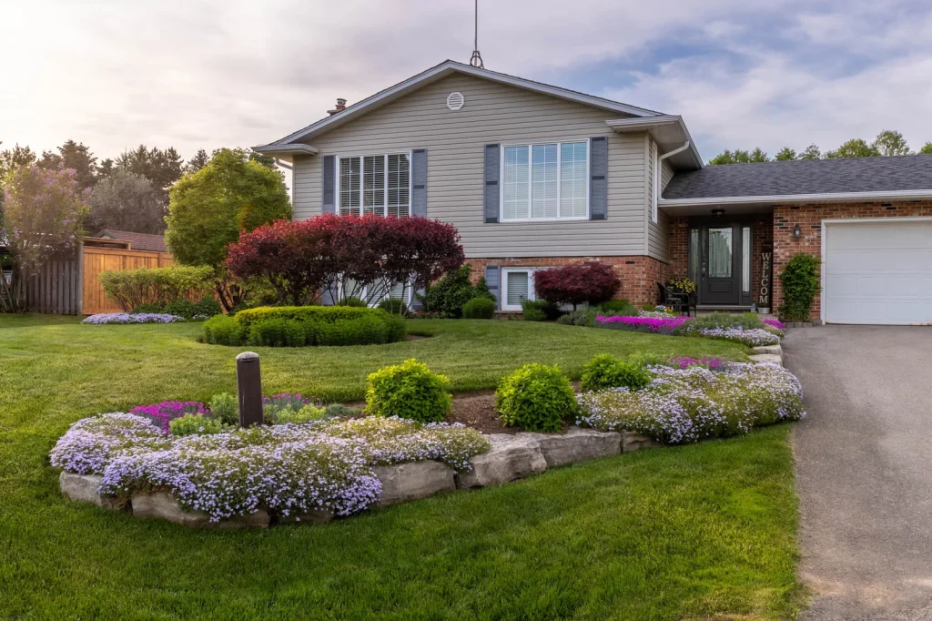 Split-level home with a landscaped front yard, stone-edged flower bed and lawn.